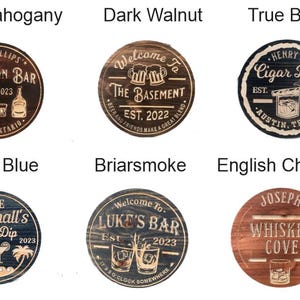 May include: A collection of six wooden bar signs in various colors, including dark mahogany, dark walnut, and navy blue. Each sign features custom text and graphics, such as "Bourbon Bar" and "Cigar Bar."