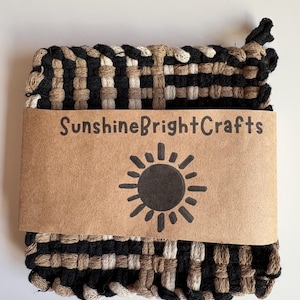 May include: Woven square pot holder in black, tan, and cream colors. A brown paper label with the text "SunshineBrightCrafts" and a sun graphic is attached to the pot holder.