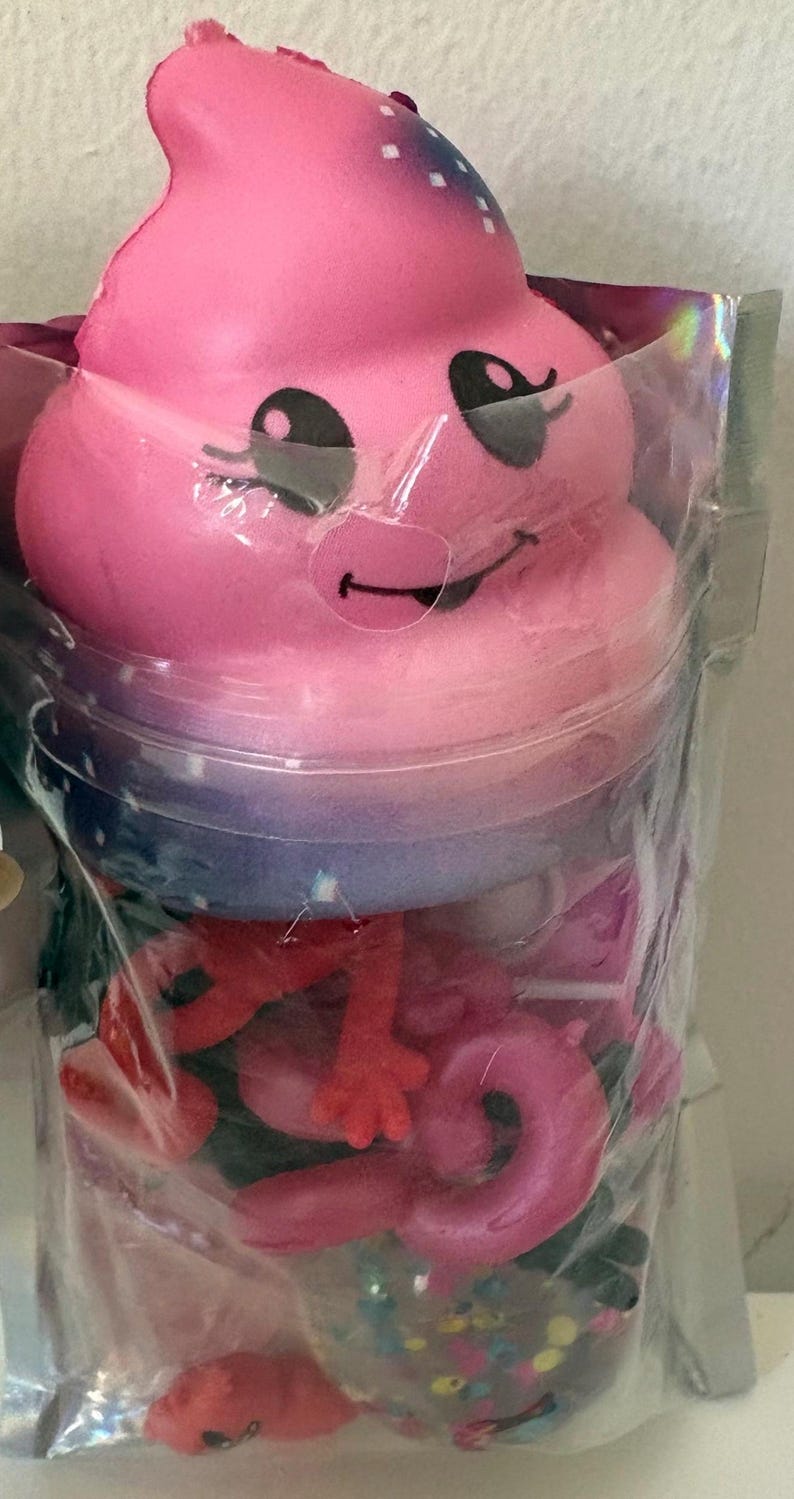 May include: A pink squishy toy shaped like a smiling swirl with black eyes and a mouth, packaged in a clear plastic bag containing various small red and pink plastic animal figures and colorful confetti pieces visible through the transparent material.