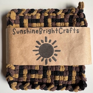 May include: A square, woven hot pad in shades of brown, black, and tan. The hot pad is wrapped with a brown paper band that reads "SunshineBrightCrafts" and features a sun graphic.