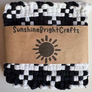 May include: A square, woven potholder in a black and white checkerboard pattern. A brown paper band wraps around the potholder, with the text "SunshineBrightCrafts" and a sun graphic.