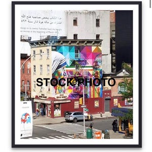 May include: A street scene featuring a colorful mural on a building, with text in Arabic and English. The mural includes geometric shapes and portraits. A store with the text "Chelsea Square Market" is visible.