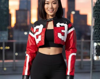 May include: A cropped red, black, and white leather jacket with the number 23 on the front. The jacket has a black collar and white stripes. The person is wearing a black top and black leggings.