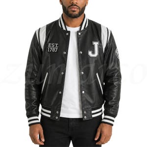 May include: Black varsity jacket with white accents on the shoulders, collar, and cuffs. Features a white "J" patch and "EST. 1787" text. The jacket has a button-up front and a ribbed hem.