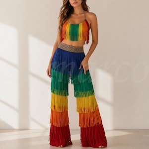 Puede incluir: Un conjunto de top corto y pantalones de pierna ancha con flecos de colores del arcoíris. El top tiene tirantes halter y un diseño de flecos en capas en rojo, naranja, amarillo, verde y azul. Los pantalones presentan un diseño de flecos similar.