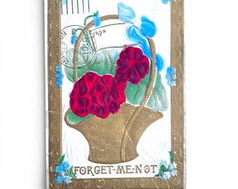 Postal A16 con cesta de flores de satén dorado con relieve grueso y la inscripción "No me olvides" – Enviada en 1910 – Sello al revés – Postal antigua inusual