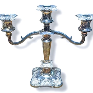 Puede incluir: Un candelabro de plata de tres brazos con detalles ornamentados y una base decorativa.