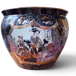 May include: A decorative, round ceramic bowl with a black rim and a detailed, colourful illustration of people in traditional clothing. The bowl features gold accents and floral patterns, with a white and cracked background.
