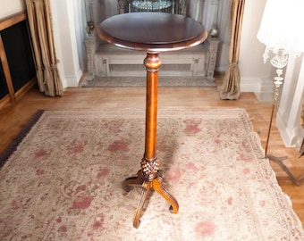 May include: A dark brown wooden pedestal table with a round top and three legs. The table is standing on a patterned rug.