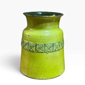 May include: A lime green ceramic vase with a flared rim and a dark green interior. The exterior features a central horizontal band decorated with a repeating square pattern of embossed four-petaled floral motifs in a darker green glaze.