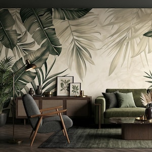 May include: A living room with a green velvet sofa, a wooden cabinet, and a gray armchair. The focal point is a large mural of tropical leaves in shades of green and cream. A dark green rug and a coffee table complete the scene.