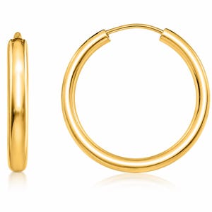 May include: A pair of polished gold hoop earrings featuring a smooth, rounded tubular design. One earring is shown from a side profile view, while the other is displayed from the front, showcasing the circular shape and the continuous metal loop.