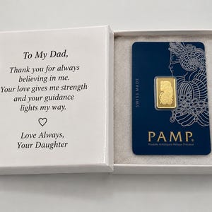 Puede incluir: Una caja de regalo blanca que contiene una peque&ntilde;a barra de oro en una tarjeta azul PAMP. La tapa interior presenta el texto: To My Dad, Thank you for always believing in me. Your love gives me strength and your guidance lights my way. Love Always, Your Daughter.
