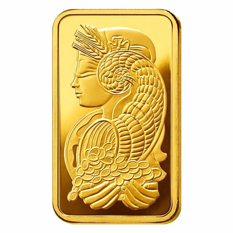 Puede incluir: Un lingote de oro rectangular con un dise&ntilde;o en relieve de una figura de perfil que lleva un tocado con espigas de trigo y sostiene un cuerno de la abundancia lleno de monedas. La superficie tiene un acabado met&aacute;lico pulido y brillante.