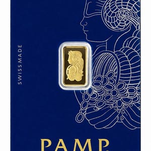 Puede incluir: Un lingote de oro rectangular encapsulado en una tarjeta protectora azul. El lingote presenta un relieve de una mujer con un cuerno de la abundancia. La tarjeta muestra el texto SWISS MADE, PAMP y Produits Artistiques Metaux Precieux.