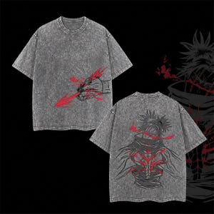 May include: A grey acid-wash t-shirt with graphic designs on the front and back. The front features a hand holding a red arrow, and the back shows a character with red detailing. The shirt has a crew neck and short sleeves.