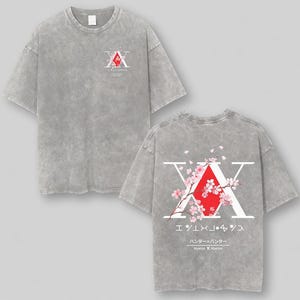 May include: Gray t-shirt featuring a graphic design on the front and back. The front design includes a red diamond shape with white text and Japanese characters. The back design features a large white "X" with a red diamond and cherry blossom branches.