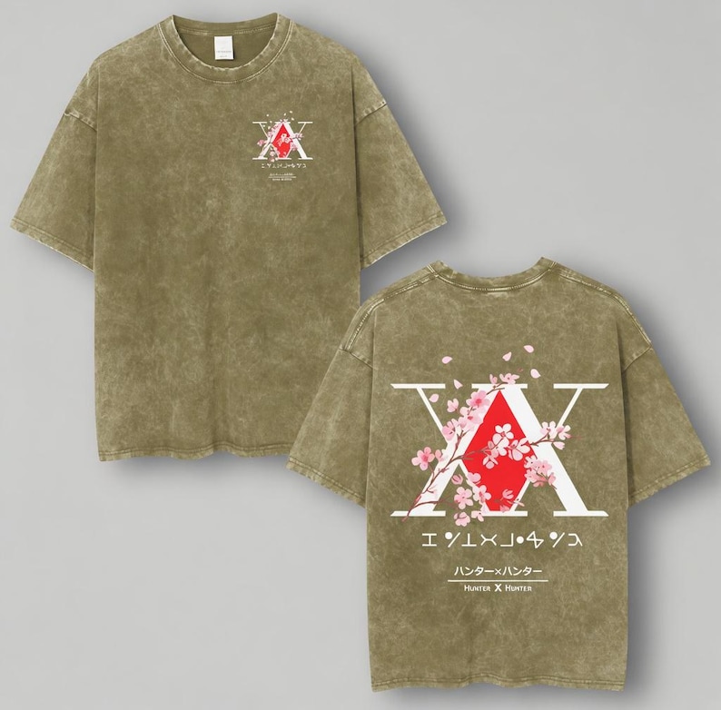 May include: Olive green t-shirt featuring a graphic design on the front and back. The front design includes a red and white emblem with Japanese text. The back design features a large white "X" with a red diamond, cherry blossoms, and Japanese text. The text "Hunter x Hunter" is also visible.
