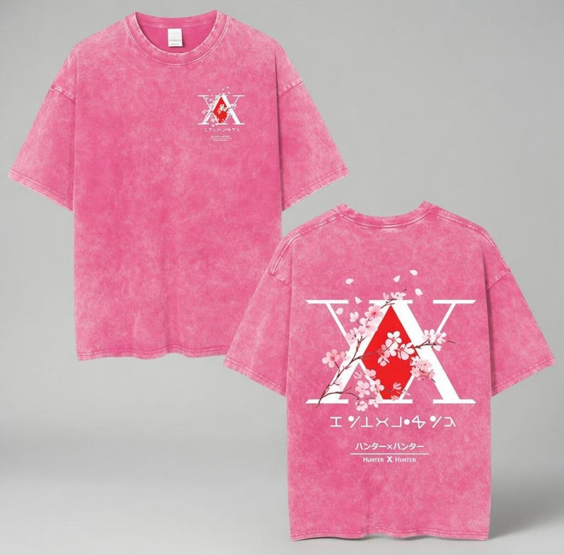May include: Pink t-shirt with a distressed wash effect. The front features a white and red graphic. The back displays a large white "X" with a red center, cherry blossom branches, and Japanese text. The shirt is short-sleeved.