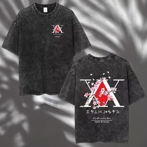 May include: Dark gray t-shirt featuring a graphic design from the anime series Hunter x Hunter. The front displays a stylized "A" with Japanese text, while the back showcases a larger design with cherry blossoms and the series title.