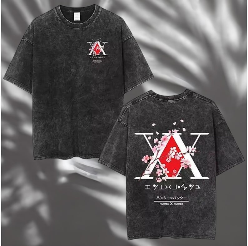 May include: Dark gray t-shirt featuring a graphic design from the anime series Hunter x Hunter. The front displays a stylized "A" with Japanese text, while the back showcases a larger design with cherry blossoms and the series title.