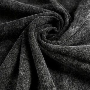 May include: Close-up of a dark gray fabric with a textured surface. The fabric is draped and folded, creating shadows and highlights. The material appears to be soft and possibly woven, with a subtle pattern visible.