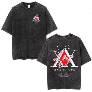 May include: Dark grey t-shirt featuring a graphic design with the letter "X" and Japanese text. The design includes a red triangle and pink cherry blossoms. The shirt has a vintage, washed appearance.