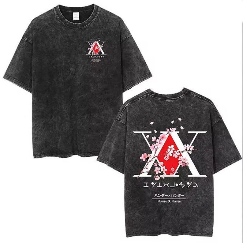 May include: Dark grey t-shirt featuring a graphic design with the letter "X" and Japanese text. The design includes a red triangle and pink cherry blossoms. The shirt has a vintage, washed appearance.