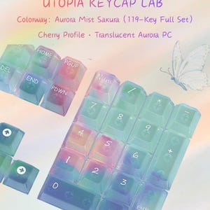 May include: A 119-key full set of translucent Aurora PC keycaps in the Aurora Mist Sakura colorway with Cherry profile. The keycaps feature a gradient of blue, green, and pink hues. Text includes UTOPIA KEYCAP LAB, Colorway: Aurora Mist Sakura.