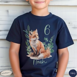 Könnte beinhalten: Ein marineblaues Kurzarm-T-Shirt mit einer Grafik eines roten Fuchses, der inmitten von grünem Blattwerk sitzt. Die Zahl 6 ist in hellgrüner Schrift über dem Fuchs gedruckt, und der Name Noah steht in hellgrüner Schreibschrift unter dem Fuchs.
