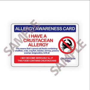 May include: A white allergy awareness card with a blue border and text. The card states "ALLERGY AWARENESS CARD" and "I HAVE A CRUSTACEAN ALLERGY". It includes a red circle with a crossed-out crab and the words "CRUSTACEAN FREE".
