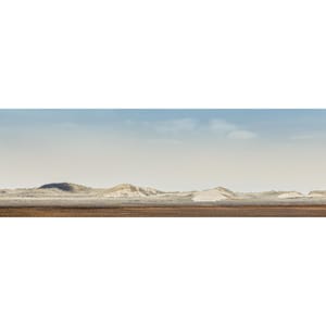 May include: A panoramic view of a sandy landscape with rolling hills and a clear blue sky. The sand dunes are covered in a thin layer of vegetation.