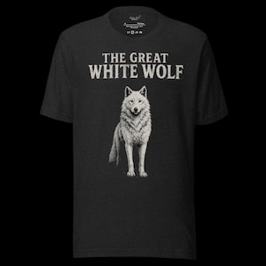 May include: Dark gray t-shirt featuring a detailed illustration of a white wolf. The text "THE GREAT WHITE WOLF" is printed above the wolf image in a bold, serif font. The shirt is made of a soft material.