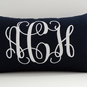 May include: A navy blue throw pillow with white embroidered monogram letters "A C H".