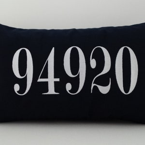 May include: A navy blue pillow with white embroidered numbers "94920" on the front.