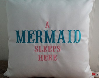 May include: White pillow with the text "A Mermaid Sleeps Here" embroidered in teal and pink.