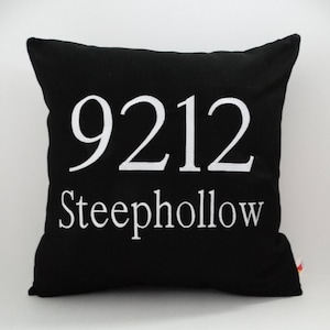 May include: Black throw pillow with white embroidered text that reads "9212 Steephollow".