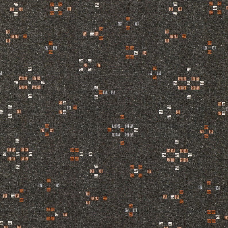 May include: A dark gray fabric with a repeating pattern of small white and orange squares. The pattern is a geometric design that resembles a star.