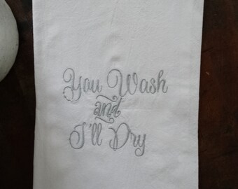 May include: White kitchen towel with the embroidered text "You Wash and I'll Dry" in a cursive font.