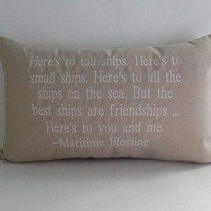 May include: Beige throw pillow with white embroidered text that reads "Here's to tall ships. Here's to small ships. Here's to all the ships on the sea. But the best ships are friendships... Here's to you and me. -Maritime Blessing"