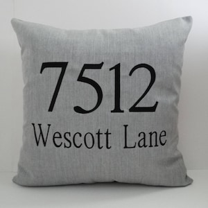 May include: A gray pillow with black embroidered text that reads "7512 Wescott Lane".