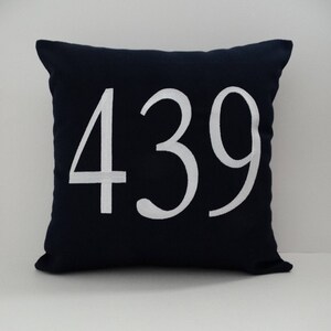 May include: A navy blue pillow with white embroidered numbers "439" on the front.