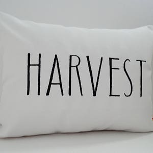Może przedstawiać: Biała poduszka z czarnym tekstem, kt&oacute;ry brzmi "HARVEST".