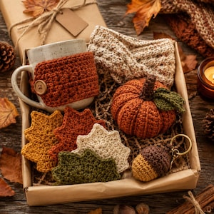 Peut inclure: Un coffret cadeau contenant une tasse en céramique mouchetée avec une housse en crochet rouille, un bandeau en crochet beige, une petite citrouille en crochet orange avec des feuilles vertes, quatre sous-verres en forme de feuille et un porte-clés gland.