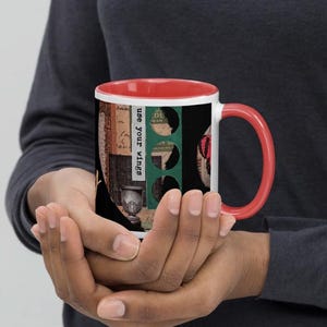 Puede incluir: Una taza de cerámica blanca con interior y asa rojos. La taza presenta un diseño de collage con las palabras "use your wings" y una urna decorativa. El diseño incluye elementos verdes, negros y rojos.