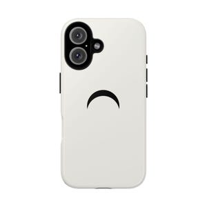 以下が含まれることがあります： 黒い三日月デザインの白い携帯電話ケース。ケースの左上にデュアルカメラがあり、側面に黒いアクセントがあります。全体的なデザインはミニマリストでモダンです。