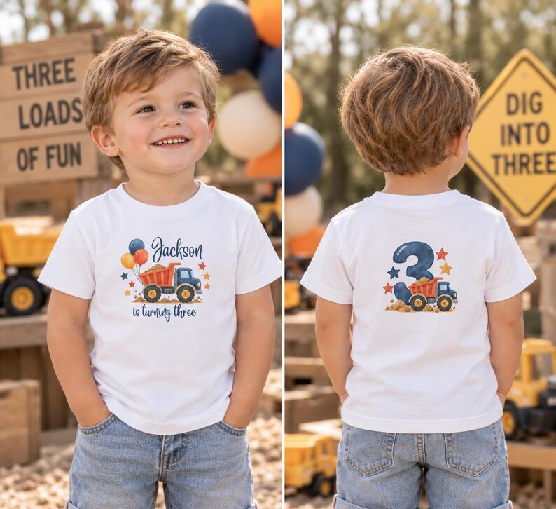 May include: A white short-sleeved t-shirt featuring a graphic of a dump truck, balloons, and the text Jackson is turning three on the front, and a large number three with a dump truck graphic on the back, paired with blue denim jeans.