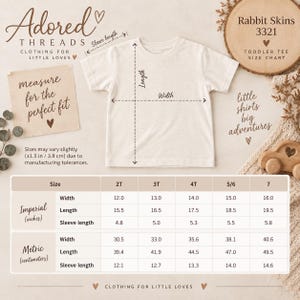 May include: A plain off-white toddler t-shirt displayed with a size chart for Rabbit Skins 3321. The chart provides width, length, and sleeve length measurements in both inches and centimeters for sizes 2T through 7, including a 1.5 inch tolerance note.