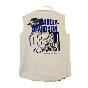 May include: White Harley-Davidson sleeveless shirt with a graphic print. The print features the Harley-Davidson logo, a checkered flag, a motorcycle racer, the number 03, and the phrase "Make 'em eat dust."