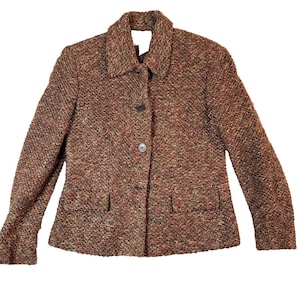 May include: A brown tweed jacket with a collared neckline and two front pockets. The jacket has a three-button closure and is made of a textured fabric with flecks of red, green, and brown.